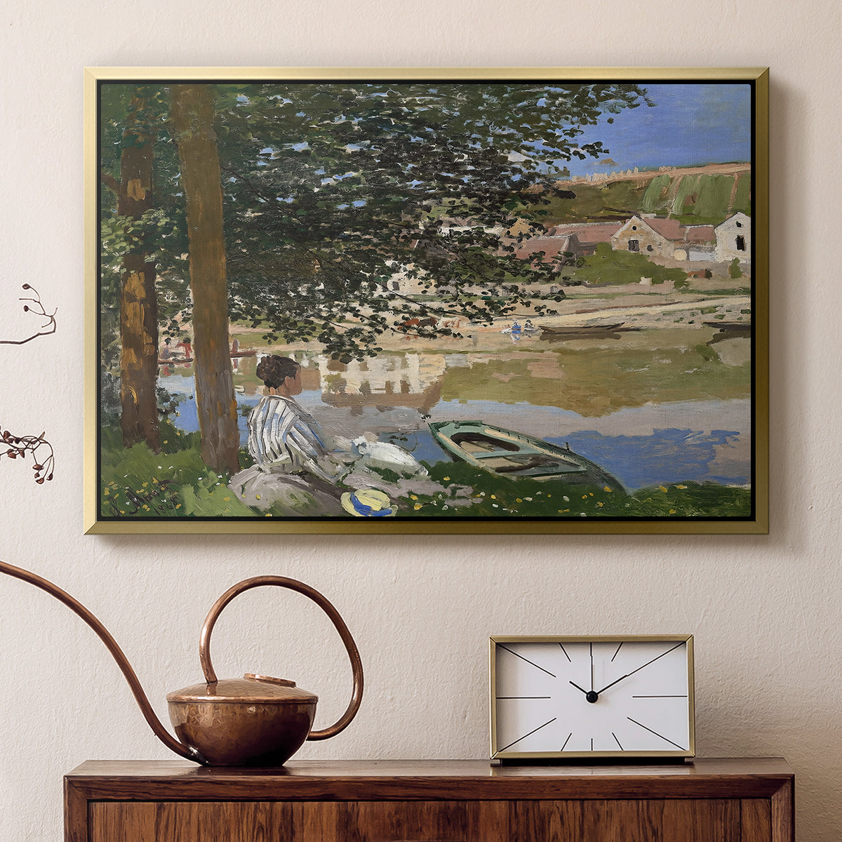 Gold floater framed canvas featuring an impressionist landscape with people relaxing along the Seine, displayed above a cabinet in a soft-toned living room.