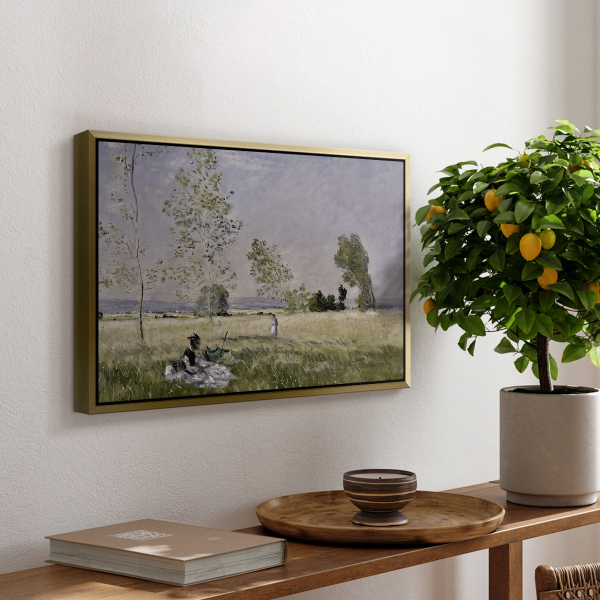 Summer (L'ete), 1874 by Claude Monet, presented in a gold floater framed canvas featuring a woman seated in grassy field beneath tree in bright summer landscape, displayed above a hallway console table.