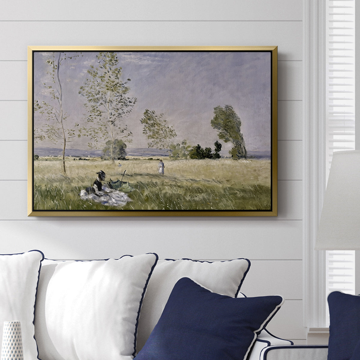 Summer (L'ete), 1874 by Claude Monet displayed above a sofa in a living room in a gold floater frame, featuring an impressionist countryside scene with figure resting in shade.