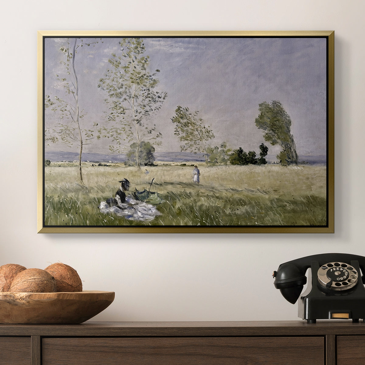 Summer (L'ete), 1874 by Claude Monet in a gold floater framed canvas displayed above a console table in a hallway, featuring a tranquil summer landscape with lone figure in nature.