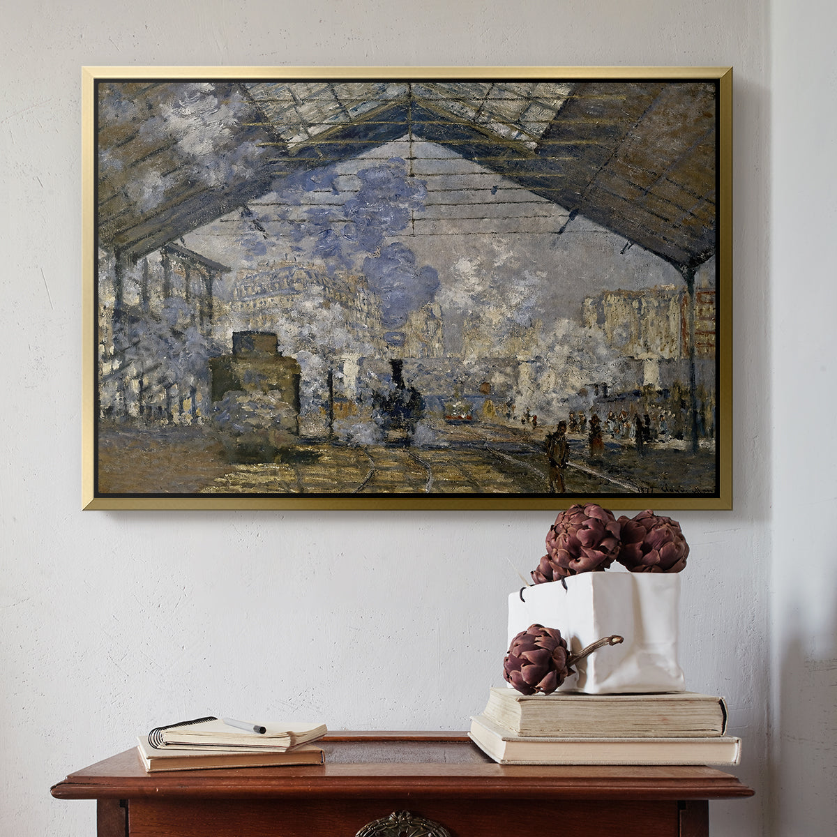 Gold floater framed canvas featuring The Gare Saint-Lazare, 1877 by Claude Monet above an entryway table in a minimalist foyer.