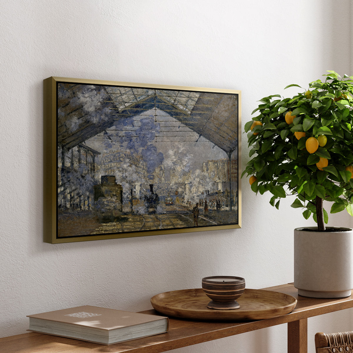 The Gare Saint-Lazare, 1877 by Claude Monet, presented in a gold floater framed canvas featuring a train station interior filled with steam and locomotives under iron structure, displayed above a hallway console table.
