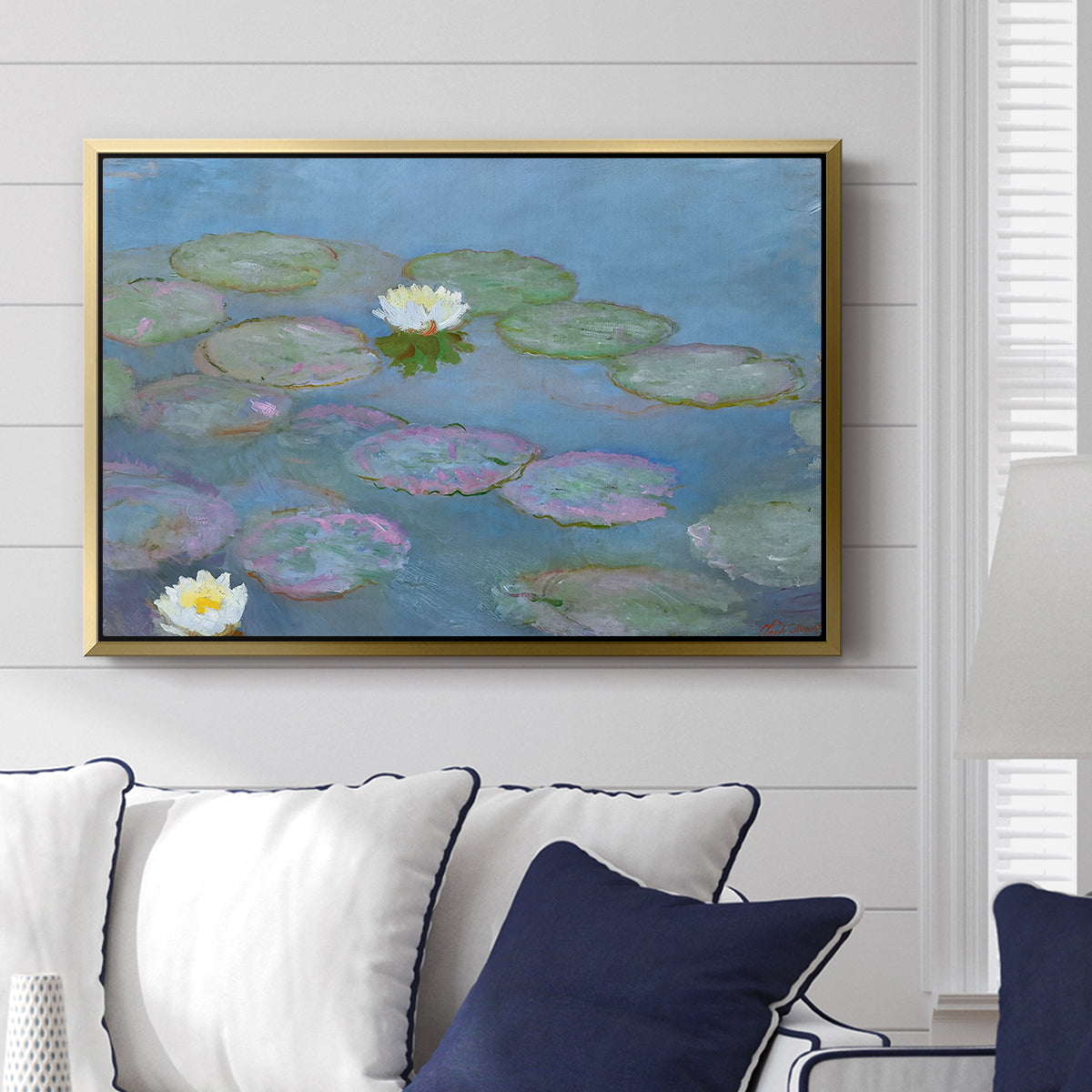 Water Lilies (Nymphéas), 1897-1899 by Claude Monet displayed above a sofa in a living room in a gold floater frame, featuring an impressionist pond scene with lily pads and soft reflections.