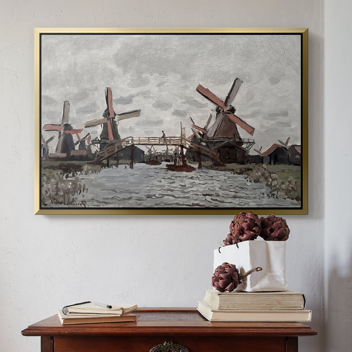 Gold floater framed canvas featuring Windmills near Zaandam, 1871 by Claude Monet above an entryway table in a minimalist foyer.