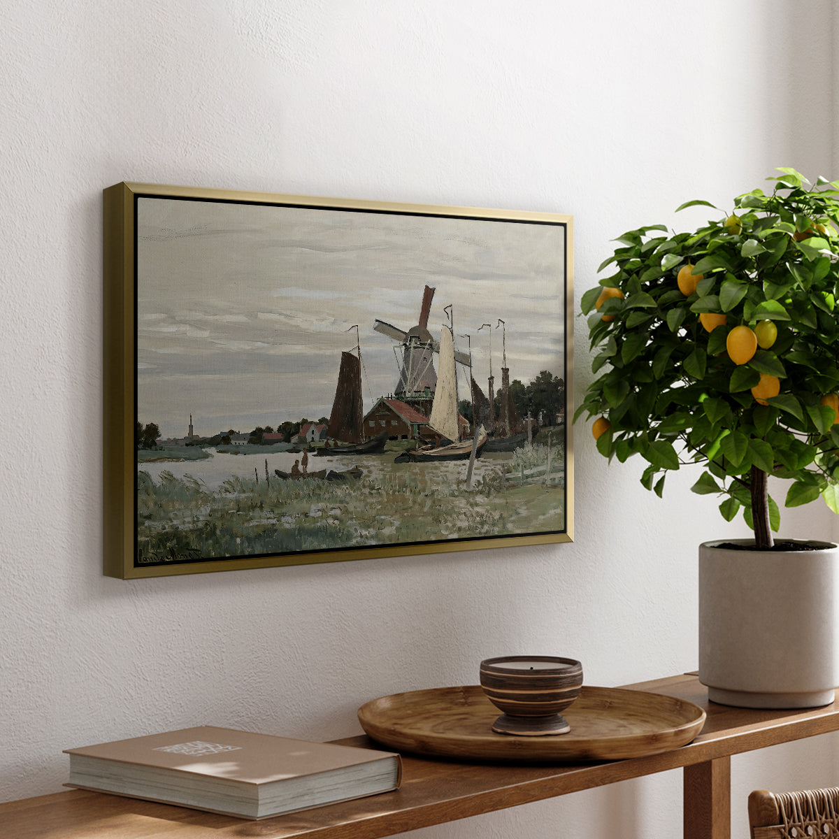 Windmill at Zaandam, 1871 by Claude Monet, presented in a gold floater framed canvas featuring a single windmill beside water with surrounding buildings and sky, displayed above a hallway console table.