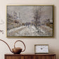Gold floater framed canvas featuring a quiet boulevard blanketed in snow with distant figures, displayed above a cabinet in a soft-toned living room.