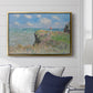 The Cliff Walk at Pourville, 1882 by Claude Monet displayed above a sofa in a living room in a gold floater frame, featuring an impressionist seaside landscape with people strolling above water.