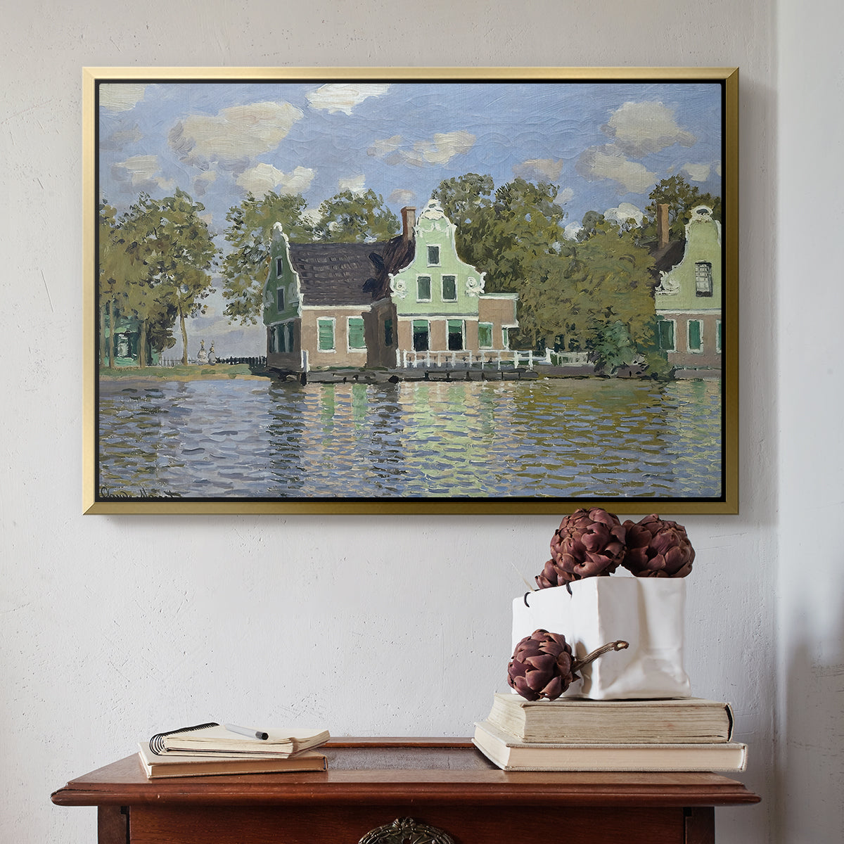 Gold floater framed canvas featuring Houses on the Zaan River at Zaandam, 1871 by Claude Monet above an entryway table in a minimalist foyer.