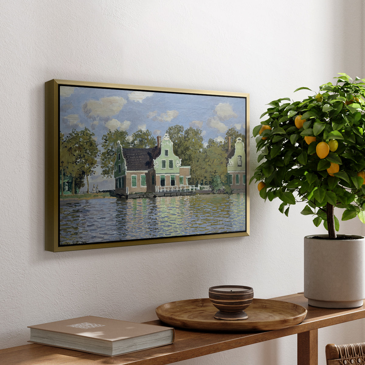 Houses on the Zaan River at Zaandam, 1871 by Claude Monet, presented in a gold floater framed canvas featuring a row of houses along river with reflections in calm water, displayed above a hallway console table.