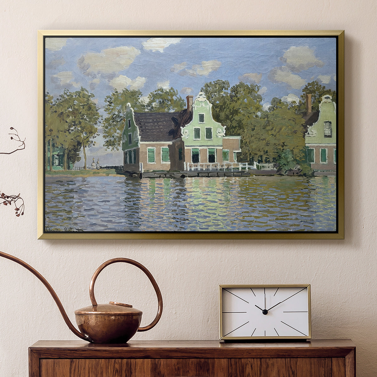 Gold floater framed canvas featuring a peaceful canal scene with houses mirrored in water, displayed above a cabinet in a soft-toned living room.