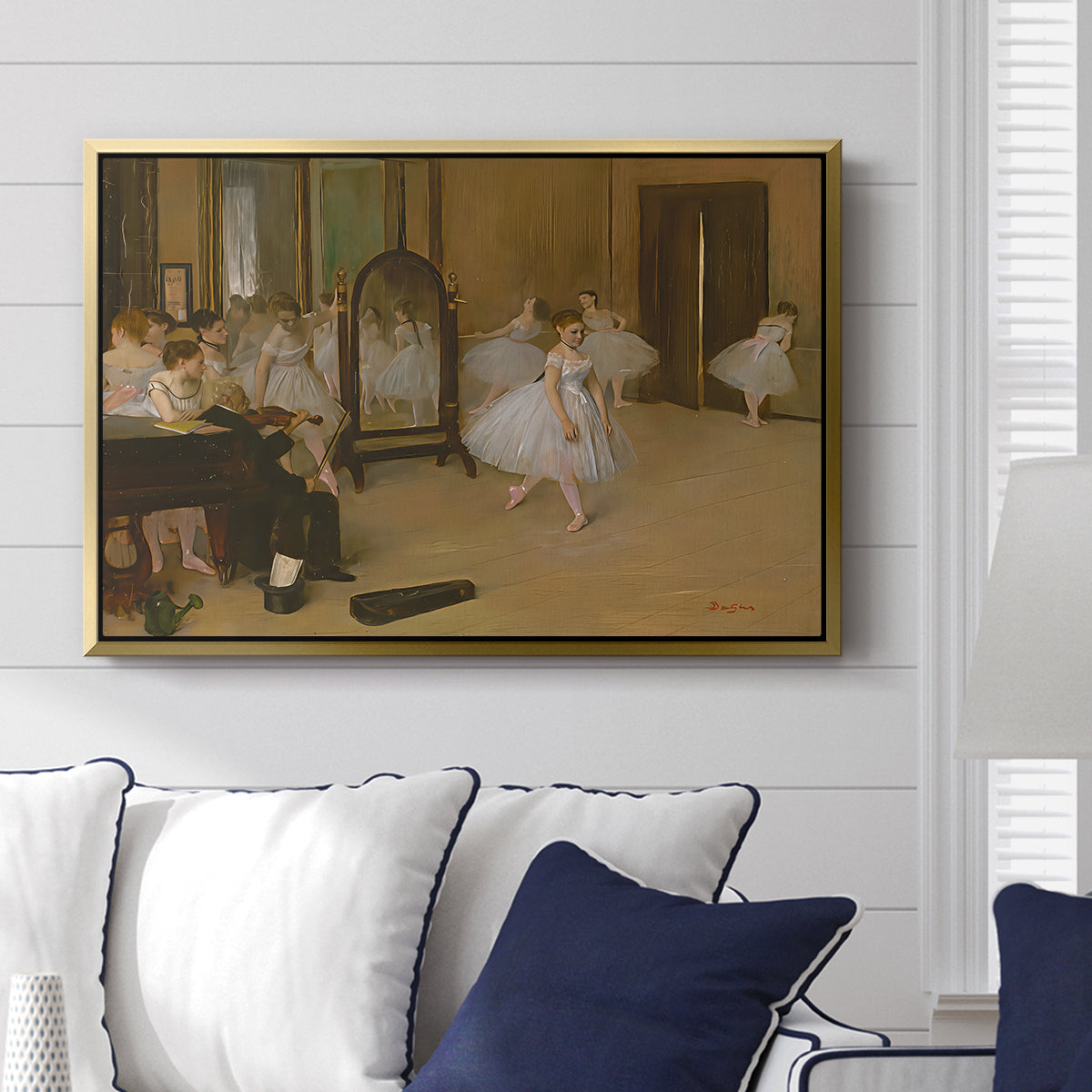 The Dancing Class, c. 1870 by Edgar Degas displayed above a sofa in a living room in a gold floater frame, featuring a rehearsal scene with ballerinas in tutus arranged in studio.