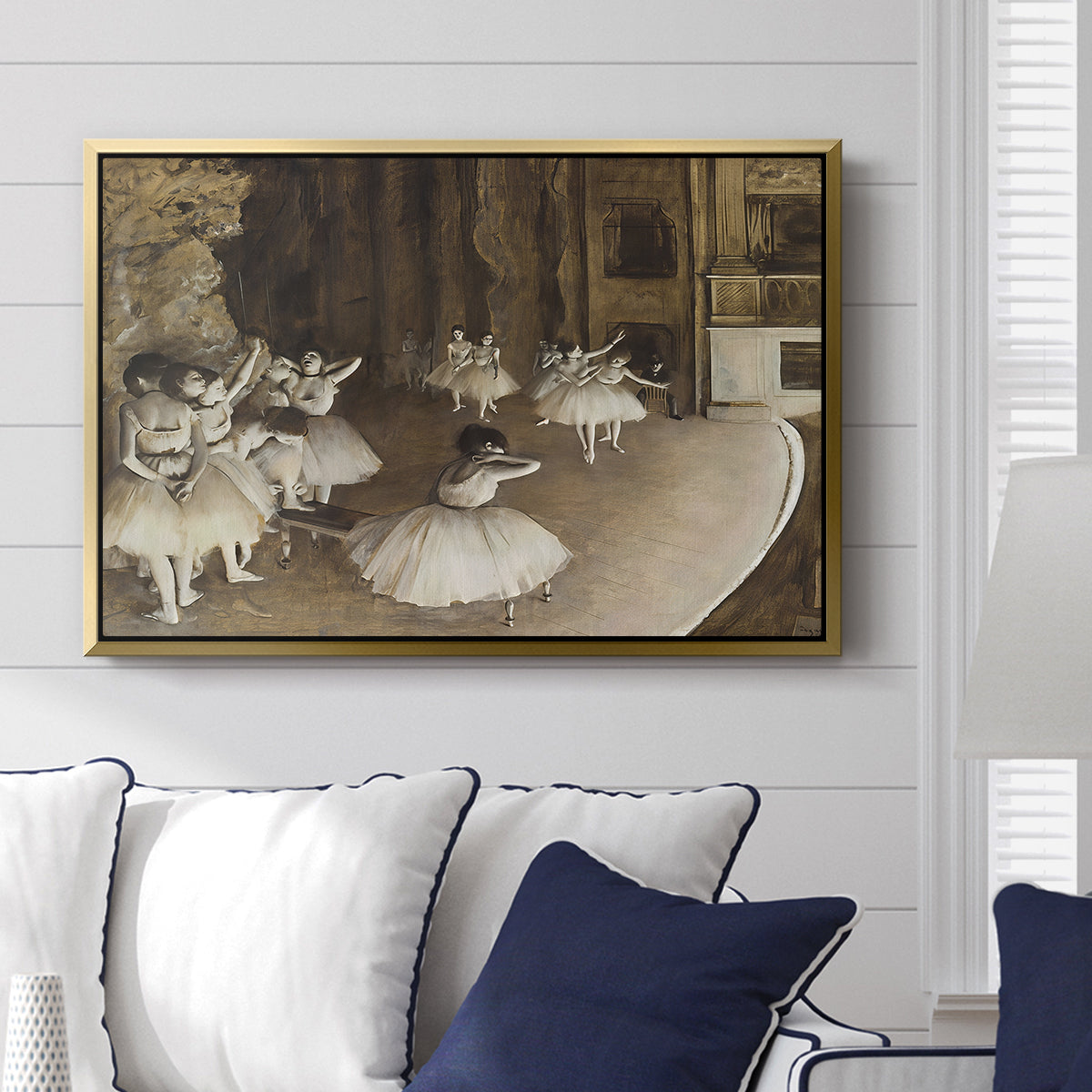 The Rehearsal of the Ballet Onstage, 1874 by Edgar Degas displayed above a sofa in a living room in a gold floater frame, featuring a stage rehearsal scene with dancers preparing performance.