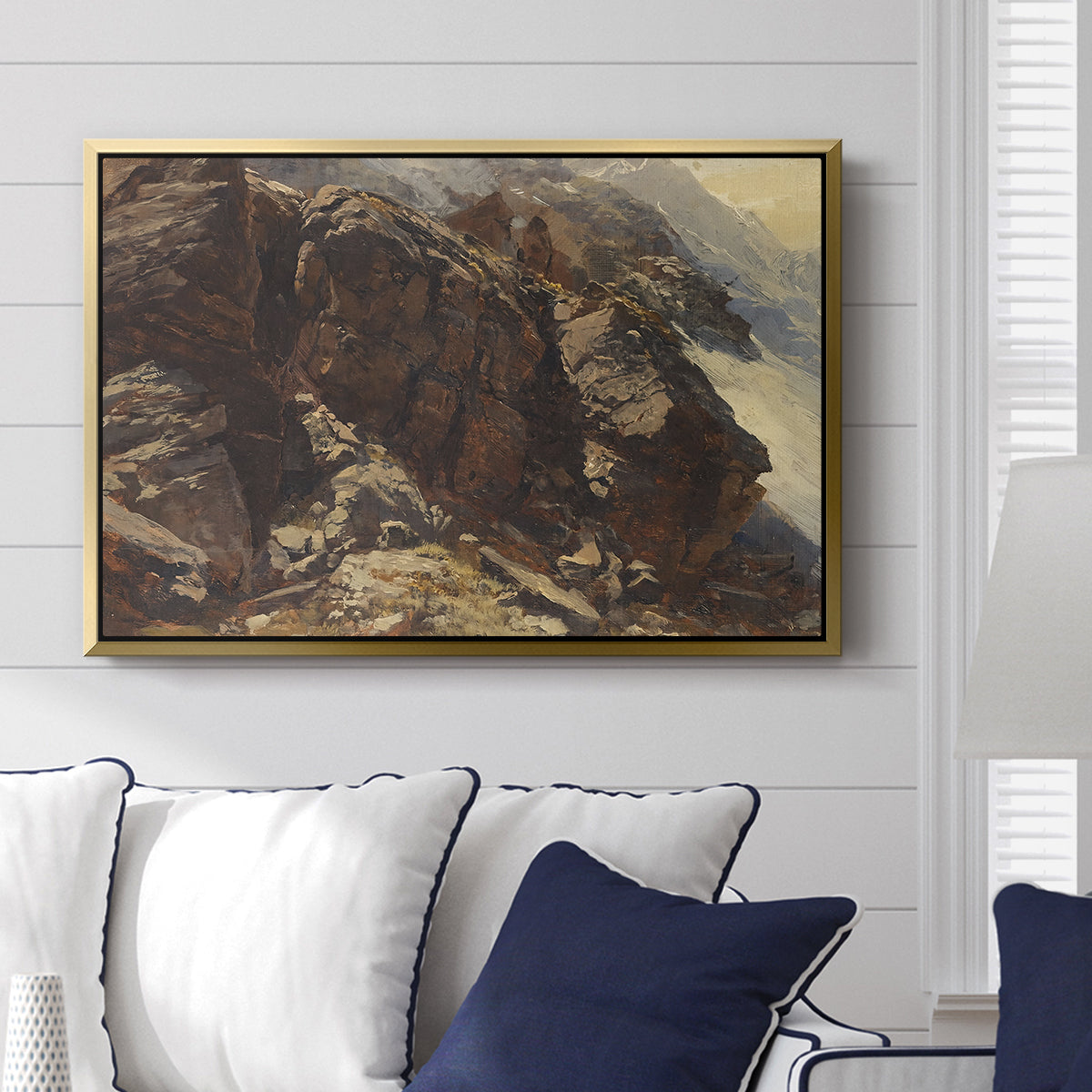 High Mountain Study, c. 1870 by Edward Theodore Compton displayed above a sofa in a living room in a gold floater frame, featuring a detailed study of rugged mountain landscape with sharp contours.