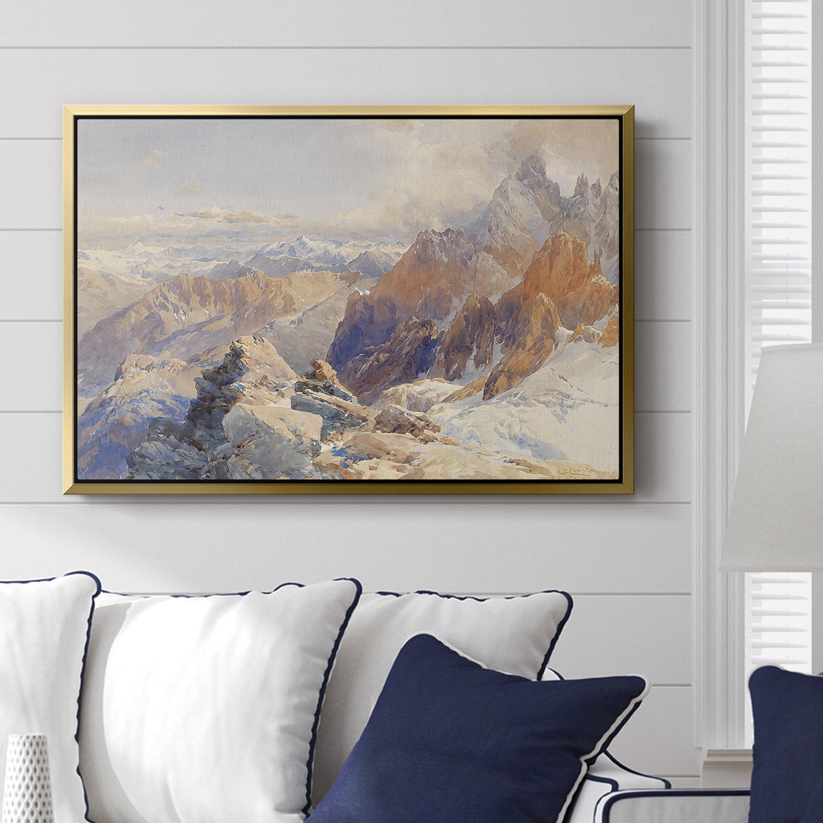 Col du Géant, 1903 by Edward Theodore Compton displayed above a sofa in a living room in a gold floater frame, featuring a high mountain landscape featuring dramatic ridges and glacier terrain.