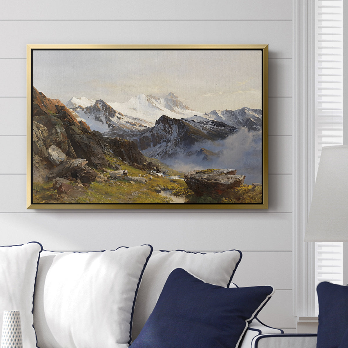 The Großglockner from the Prager Hut, 1890 by Edward Theodore Compton displayed above a sofa in a living room in a gold floater frame, featuring a mountain summit seen from elevated viewpoint with surrounding landscape.