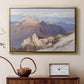 Gold floater framed canvas featuring a high vantage point overlooking rugged mountain terrain, displayed above a cabinet in a soft-toned living room.