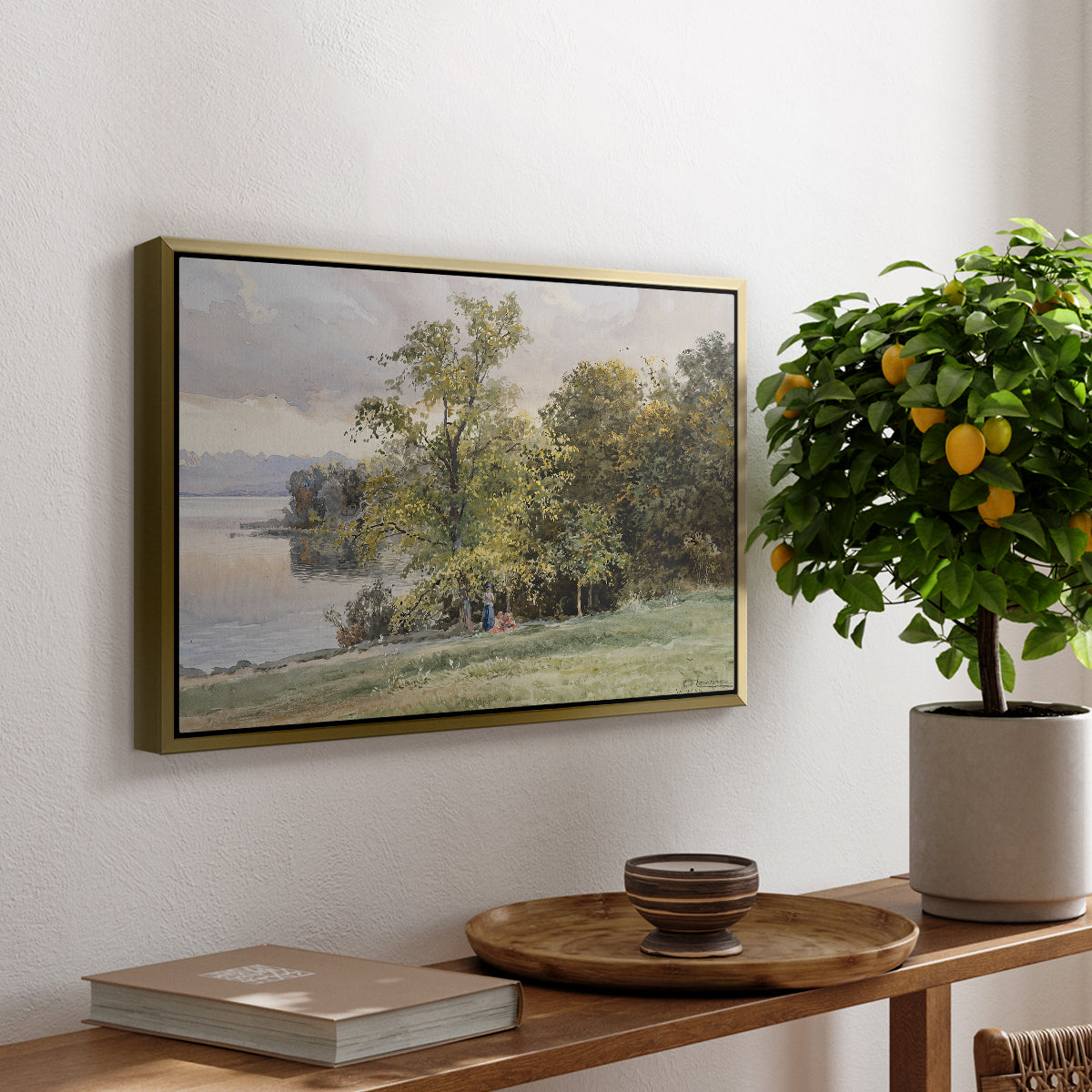 Landscape at Lake Starnberg, 1890 by Edward Theodore Compton, presented in a gold floater framed canvas featuring a lakeside landscape with calm water and trees along shoreline, displayed above a hallway console table.
