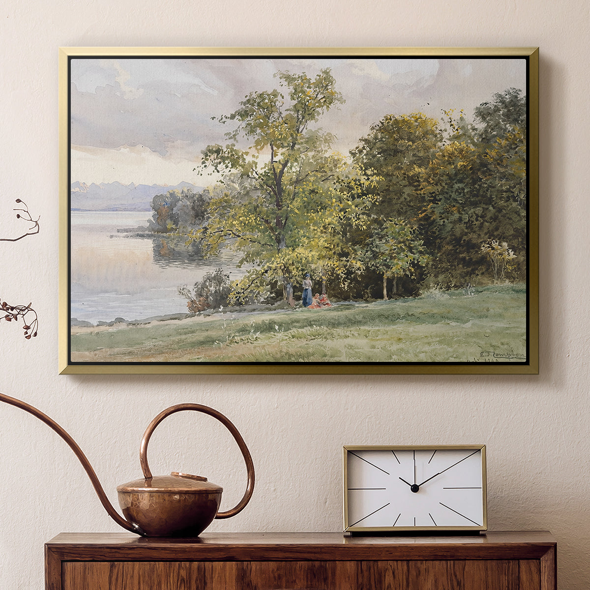 Gold floater framed canvas featuring a natural setting with water, trees, and open sky, displayed above a cabinet in a soft-toned living room.