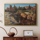 Gold floater framed canvas featuring a cityscape with classical ruins and surrounding terrain, displayed above a cabinet in a soft-toned living room.