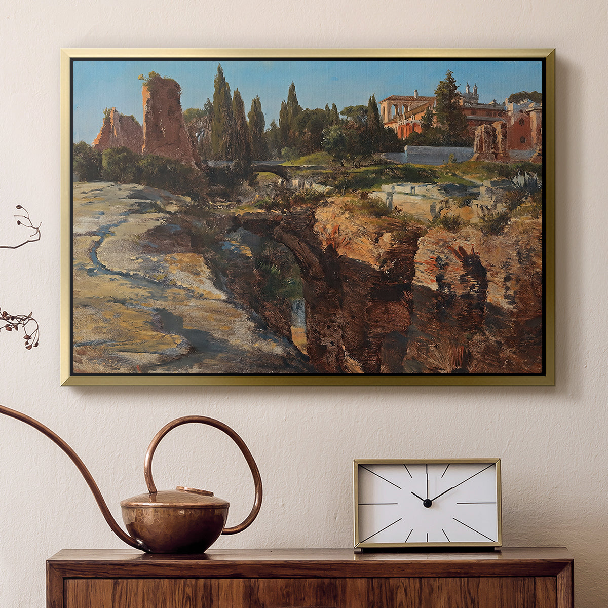 Gold floater framed canvas featuring a cityscape with classical ruins and surrounding terrain, displayed above a cabinet in a soft-toned living room.