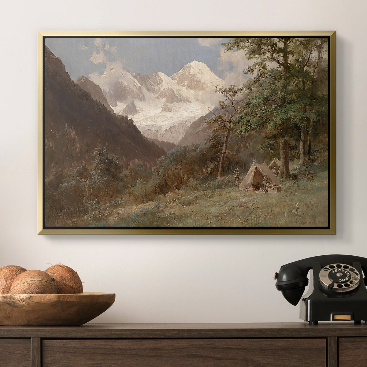 Landscape in the Caucasus, c. 1921 by Edward Theodore Compton in a gold floater framed canvas displayed above a console table in a hallway, featuring a realistic depiction of remote mountain environment.
