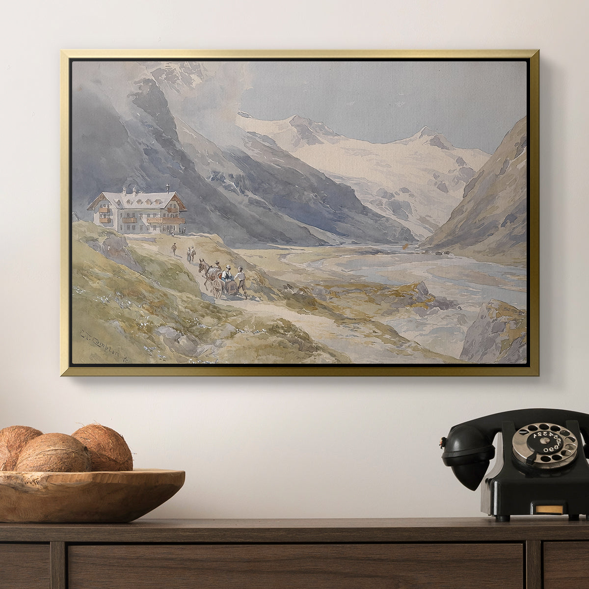 Shepherds (Pasterze), c. 1921 by Edward Theodore Compton in a gold floater framed canvas displayed above a console table in a hallway, featuring a natural landscape with human presence among mountains.
