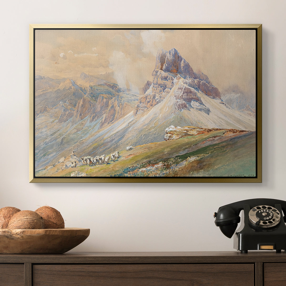 From the Dolomites, 1904 by Edward Theodore Compton in a gold floater framed canvas displayed above a console table in a hallway, featuring a realistic mountain view with strong geological forms.