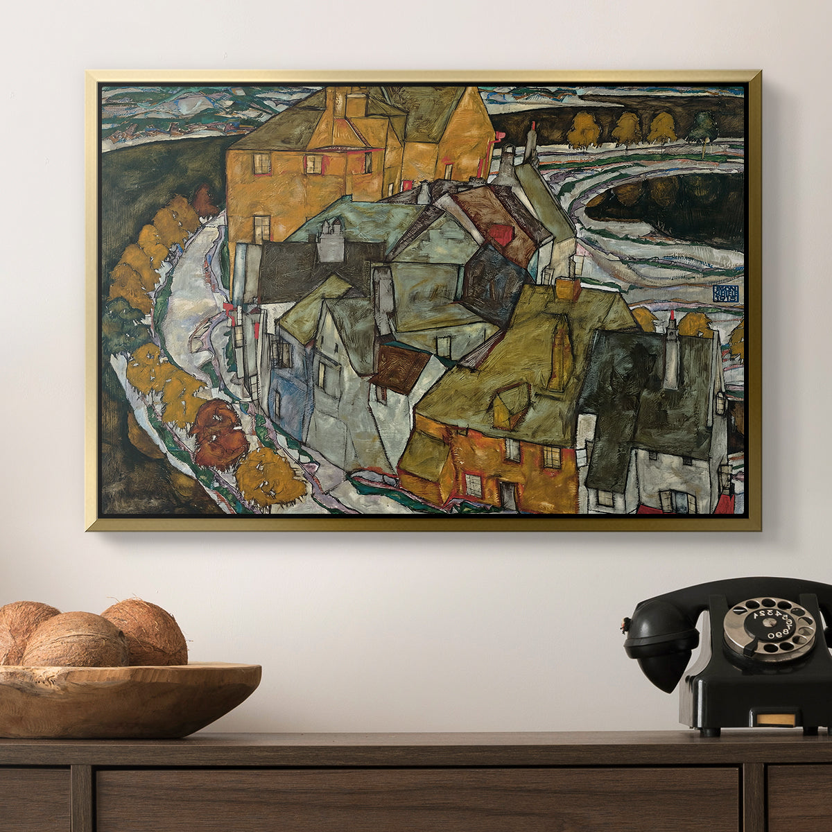 Crescent of Houses II (Island Town), 1915 by Egon Schiele in a gold floater framed canvas displayed above a console table in a hallway, featuring an architectural scene with houses arranged in curved composition.