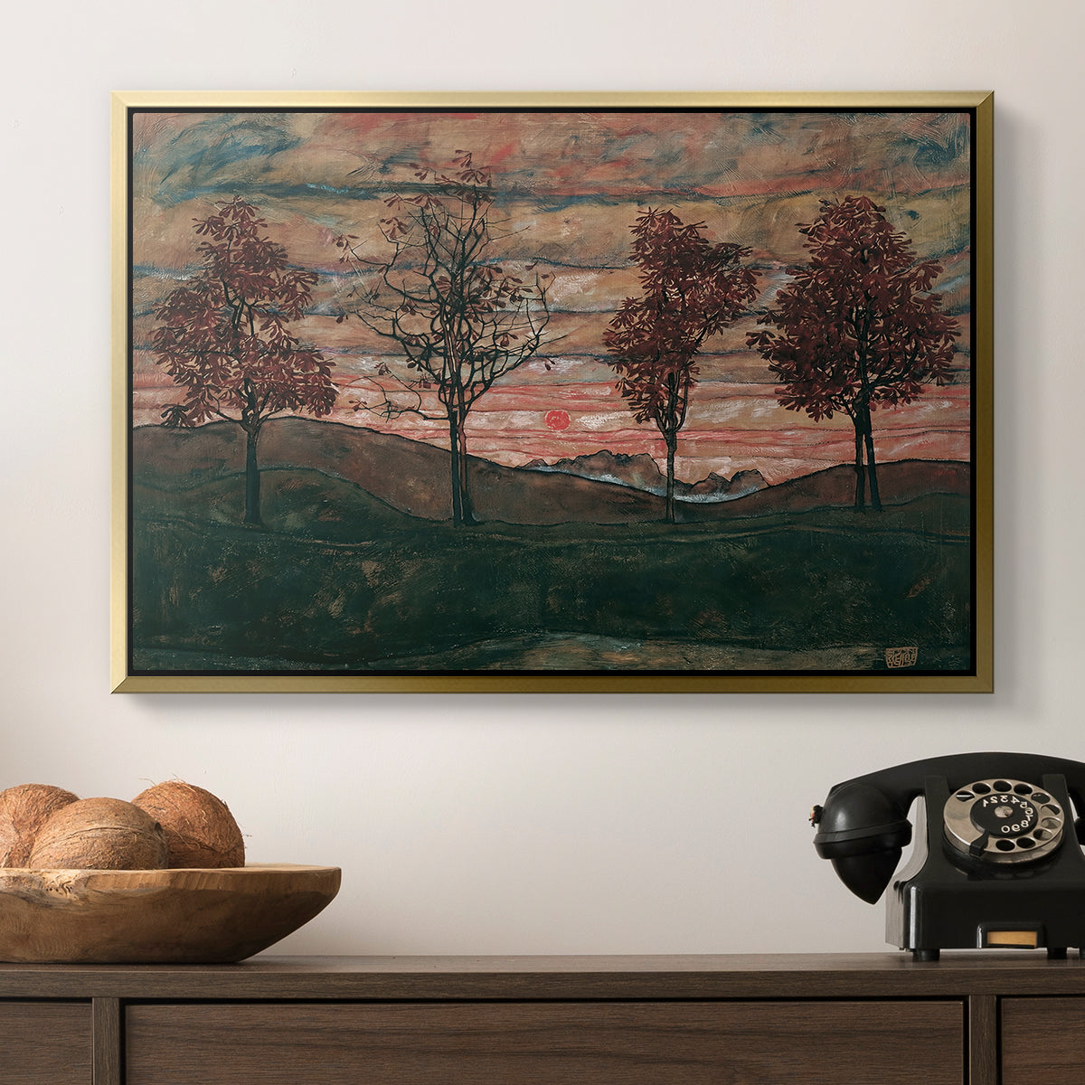 Four Trees, 1917 by Egon Schiele in a gold floater framed canvas displayed above a console table in a hallway, featuring an expressionist landscape featuring isolated trees in field.