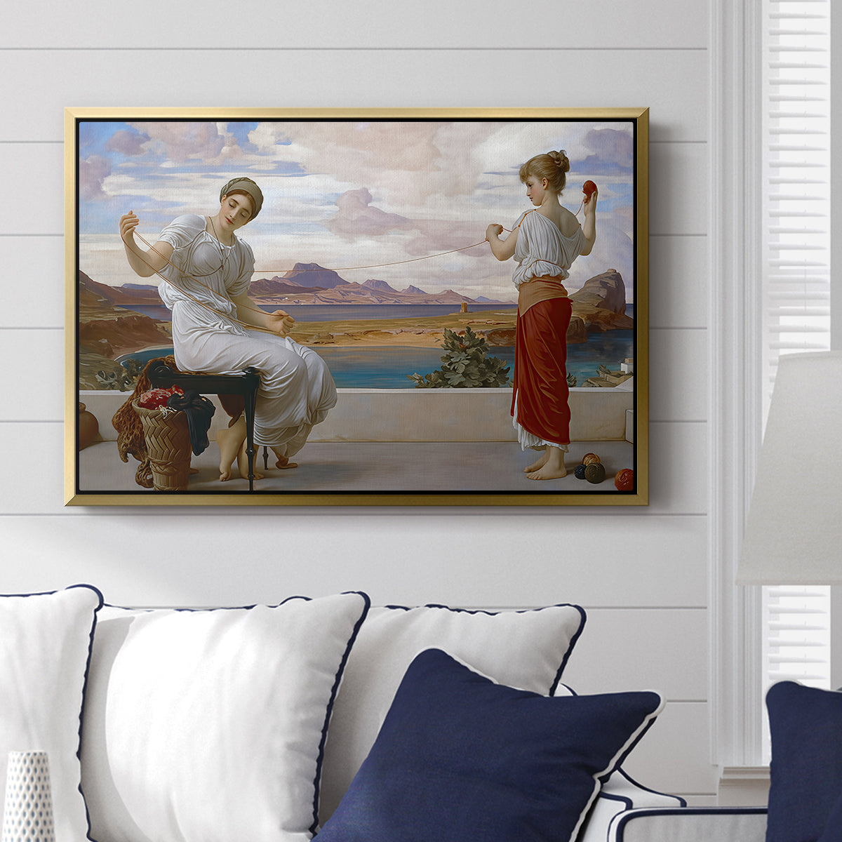 Winding the Skein, c. 1878 by Frederic Leighton displayed above a sofa in a living room in a gold floater frame, featuring two women engaged in textile work with draped garments.