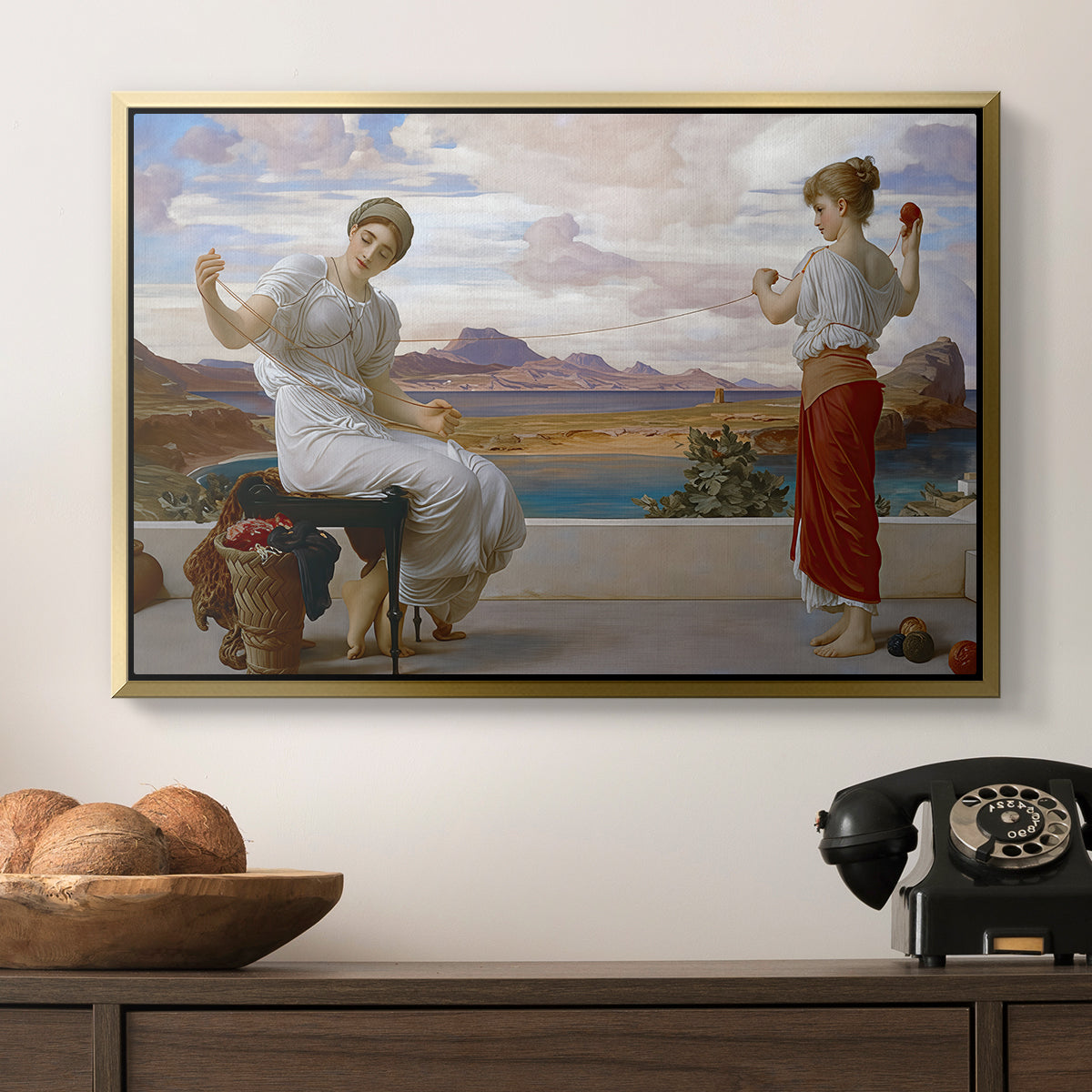 Winding the Skein, c. 1878 by Frederic Leighton in a gold floater framed canvas displayed above a console table in a hallway, featuring an elegant composition of women performing domestic task.