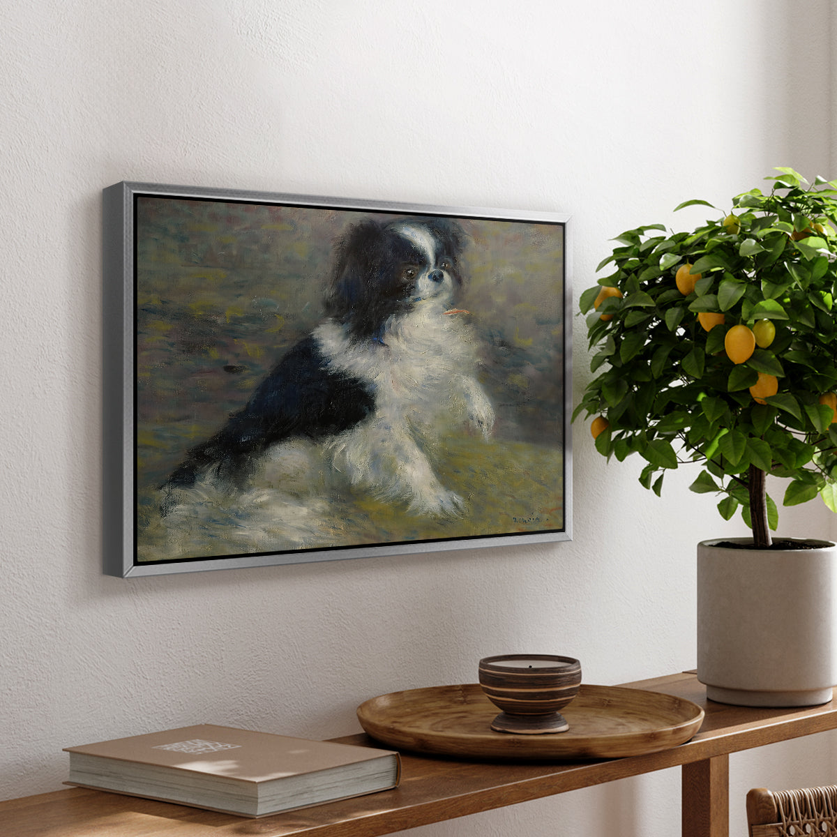 Tama, the Japanese Dog, c. 1876 by Pierre-Auguste Renoir, presented in a silver floater framed canvas featuring a small black and white dog standing in shallow water with soft brushstrokes, displayed above a hallway console table.
