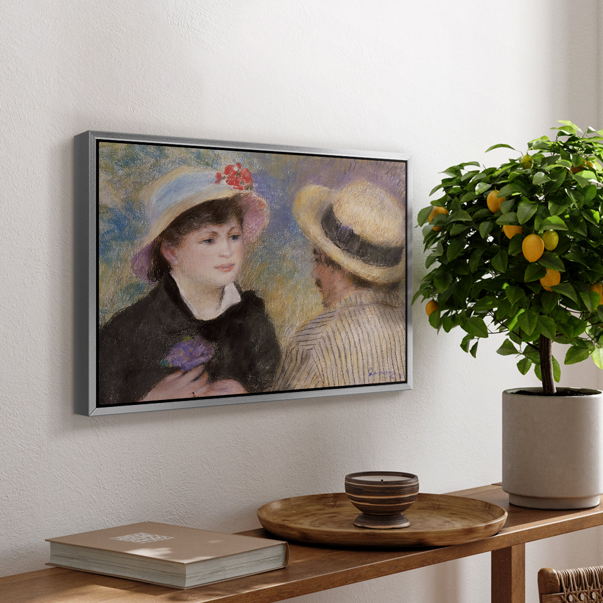 Boating Couple (Aline Charigot and Renoir), c. 1881 by Pierre-Auguste Renoir, presented in a silver floater framed canvas featuring a close-up of a couple seated together outdoors with hats and soft sunlight, displayed above a hallway console table.