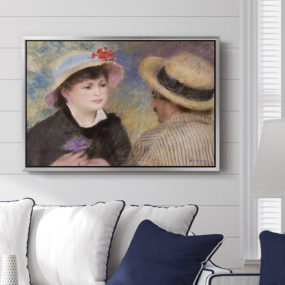 Boating Couple (Aline Charigot and Renoir), c. 1881 by Pierre-Auguste Renoir displayed above a sofa in a living room in a silver floater frame, featuring an intimate portrait of man and woman sitting side by side in outdoor setting.