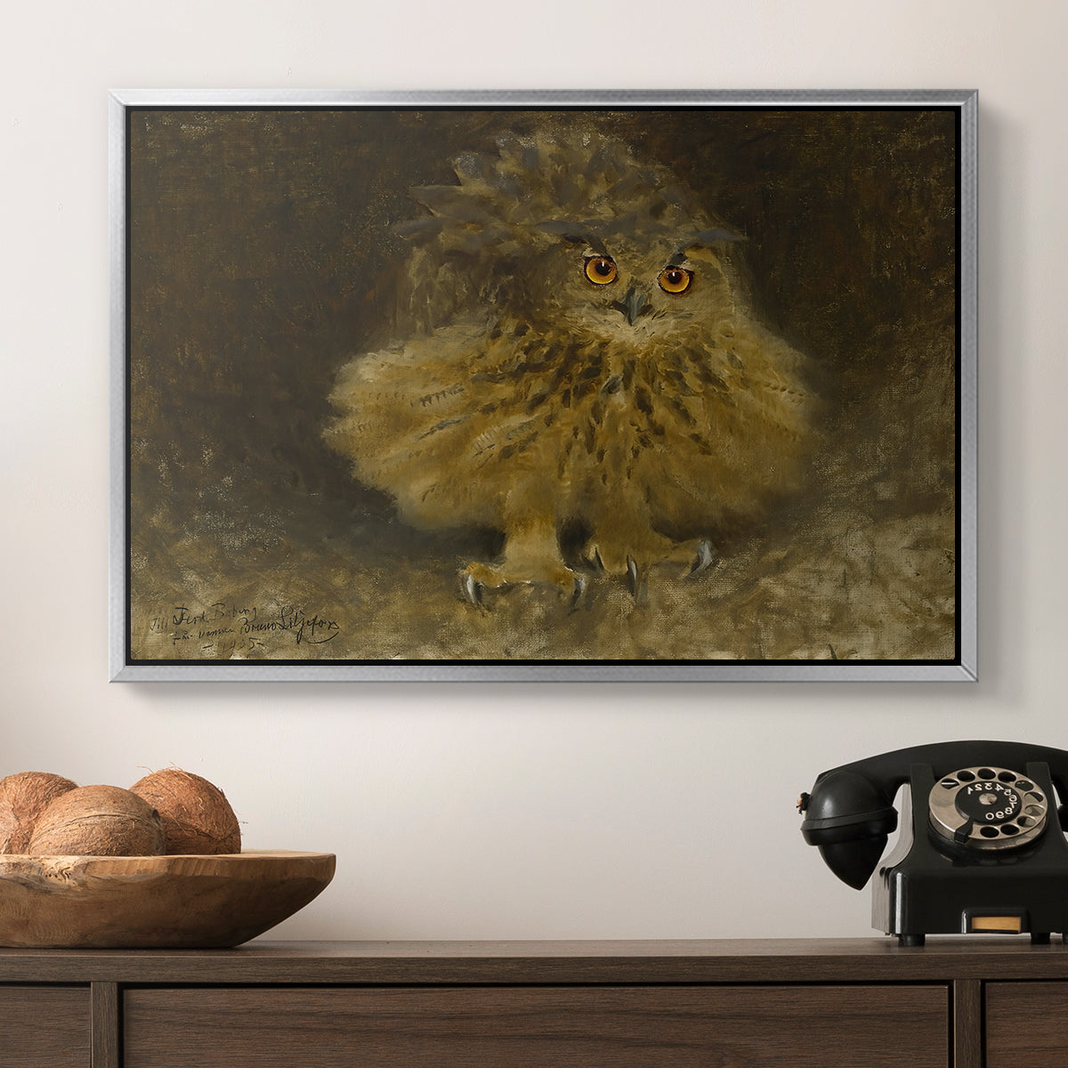 An Eagle Owl (Berguv), 1905 by Bruno Liljefors in a silver floater framed canvas displayed above a console table in a hallway, featuring a realistic depiction of owl camouflaged within woodland environment.
