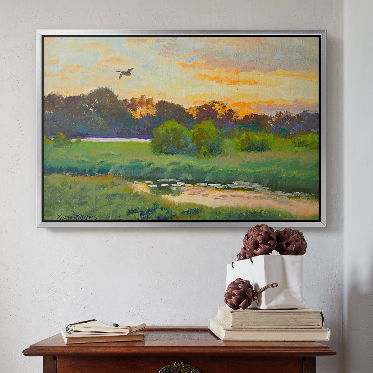Silver floater framed canvas featuring Flying Duck at Sunset, 1924 by Bruno Liljefors above an entryway table in a minimalist foyer.