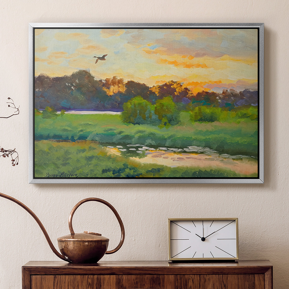 Silver floater framed canvas featuring a wild duck gliding through a golden sunset sky, displayed above a cabinet in a soft-toned living room.