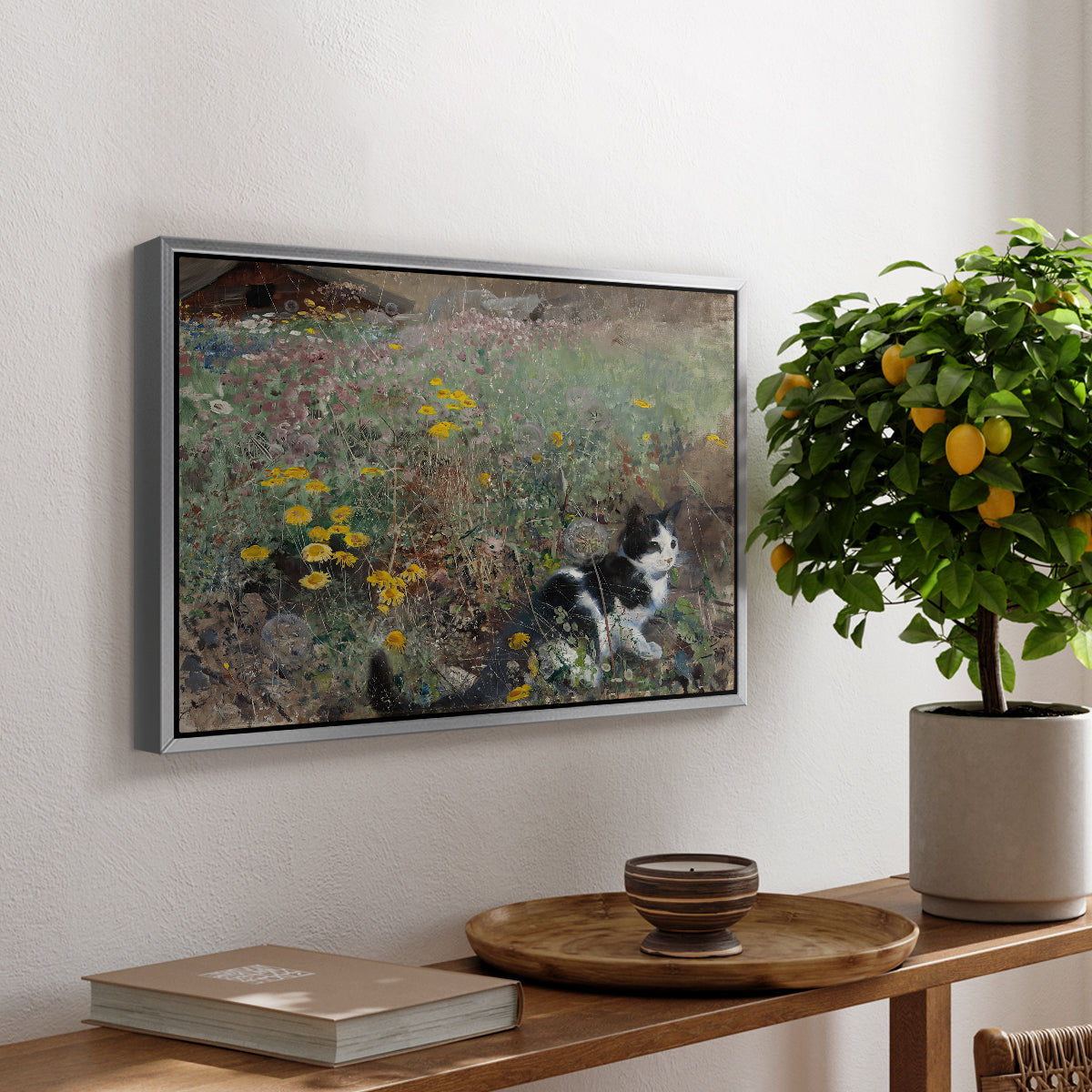 Cat on a Flowery Meadow, 1887 by Bruno Liljefors, presented in a silver floater framed canvas featuring a cat crouching in a meadow filled with wildflowers and greenery, displayed above a hallway console table.