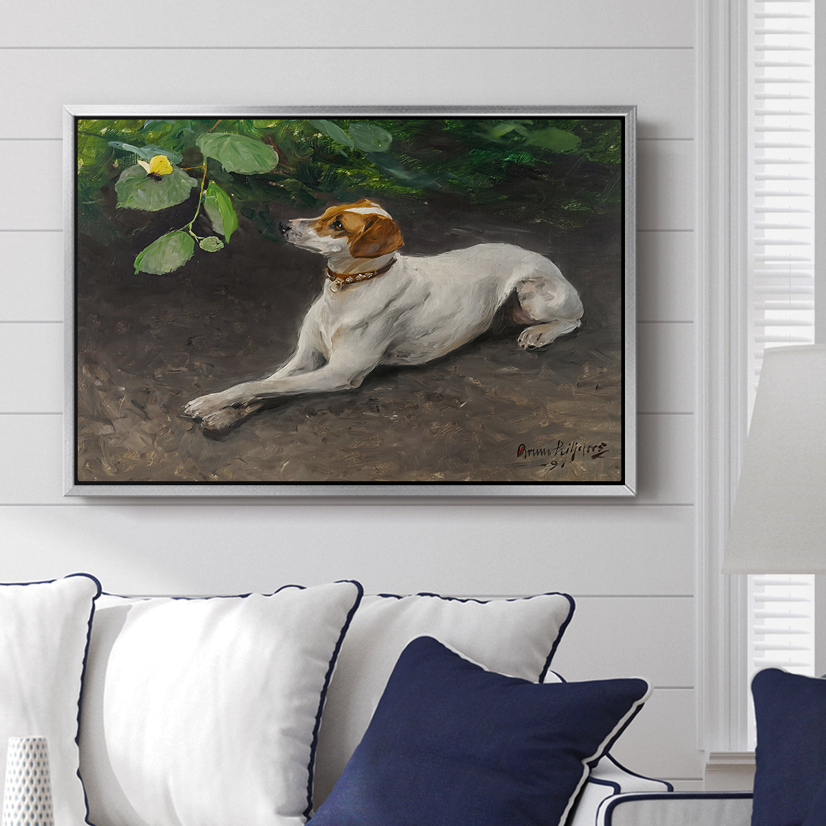 Portrait of a Dog, 1891 by Bruno Liljefors displayed above a sofa in a living room in a silver floater frame, featuring a realistic portrait of a resting dog with attentive expression.