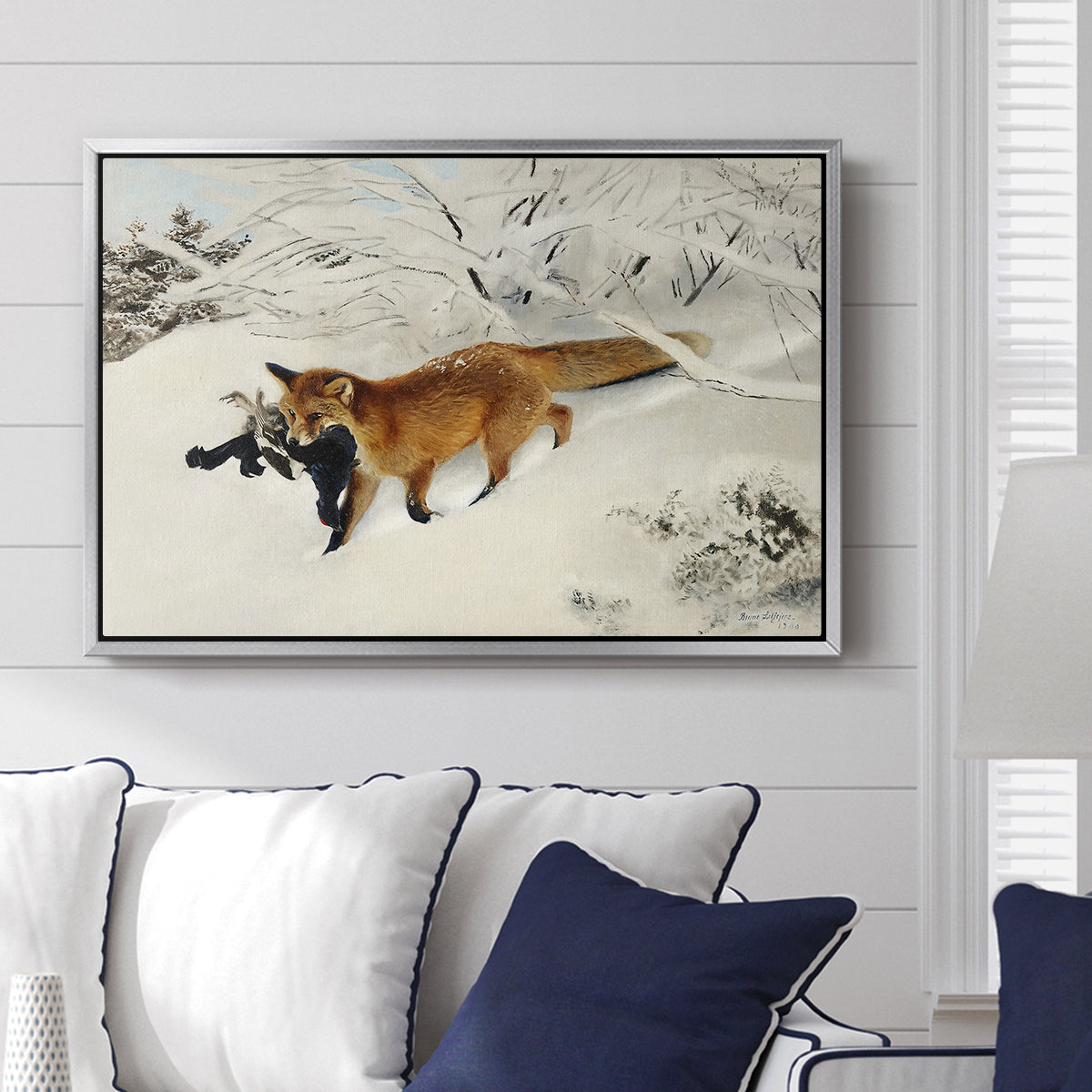 Fox in Snow Landscape, 1900 by Bruno Liljefors displayed above a sofa in a living room in a silver floater frame, featuring a wildlife scene of fox moving swiftly through winter terrain.