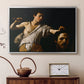 Silver floater framed canvas featuring a Baroque depiction of youth holding severed head in shadowy setting, displayed above a cabinet in a soft-toned living room.