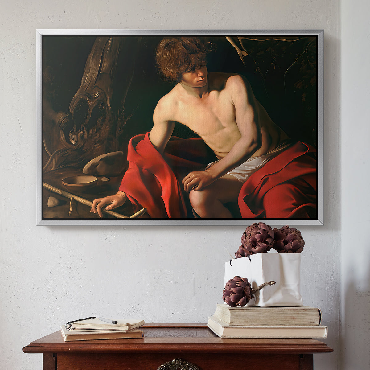 Silver floater framed canvas featuring Saint John the Baptist in the Wilderness, c. 1603-1604 by Caravaggio above an entryway table in a minimalist foyer.
