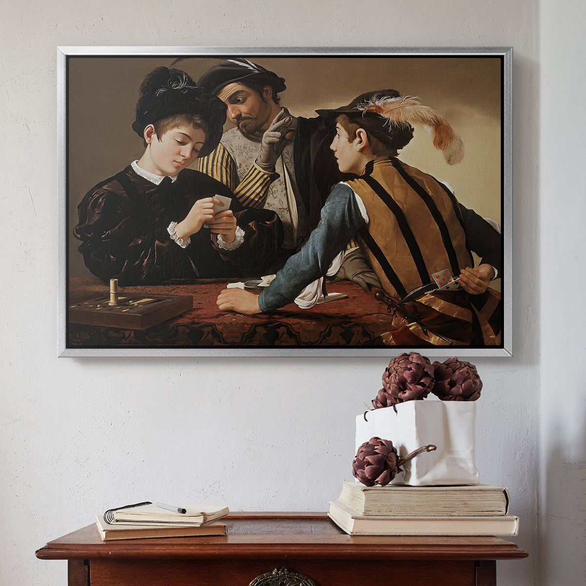 Silver floater framed canvas featuring The Cardsharps, c. 1594 by Caravaggio above an entryway table in a minimalist foyer.