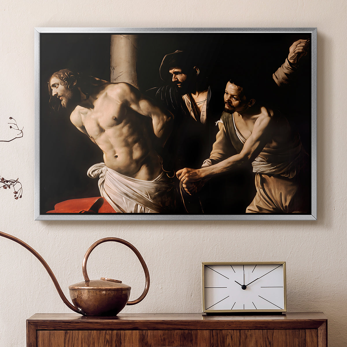 Silver floater framed canvas featuring a biblical depiction of men whipping Christ tied to pillar, displayed above a cabinet in a soft-toned living room.