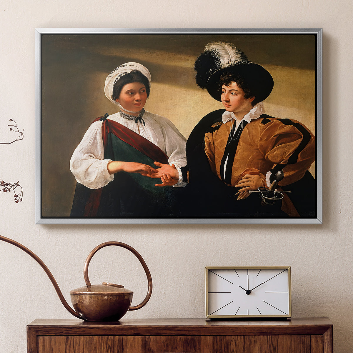 Silver floater framed canvas featuring an intimate scene of palm reading with subtle act of theft, displayed above a cabinet in a soft-toned living room.