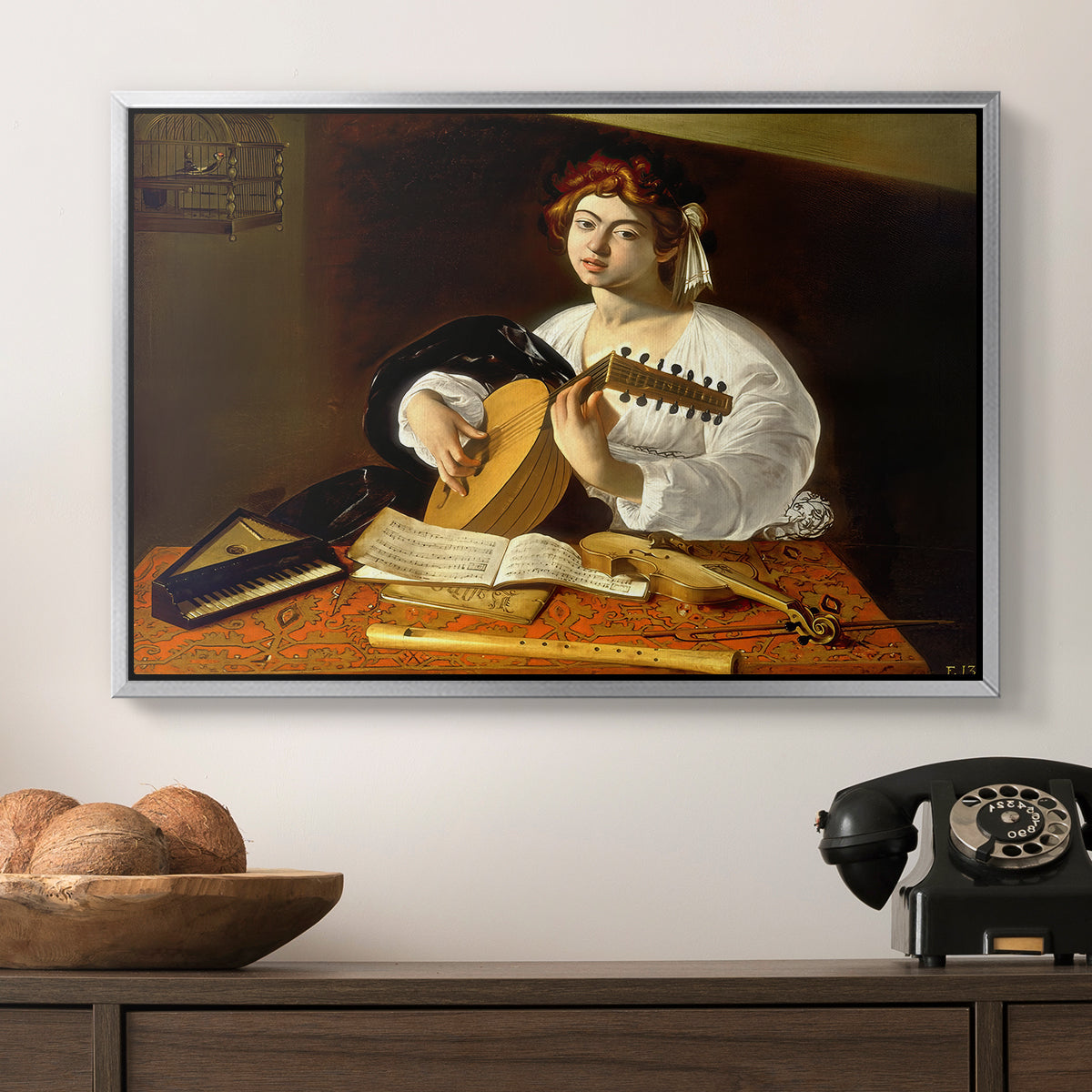 The Lute Player (Wildenstein Version), c. 1596 by Caravaggio in a silver floater framed canvas displayed above a console table in a hallway, featuring an intimate portrait of musician with still life elements.
