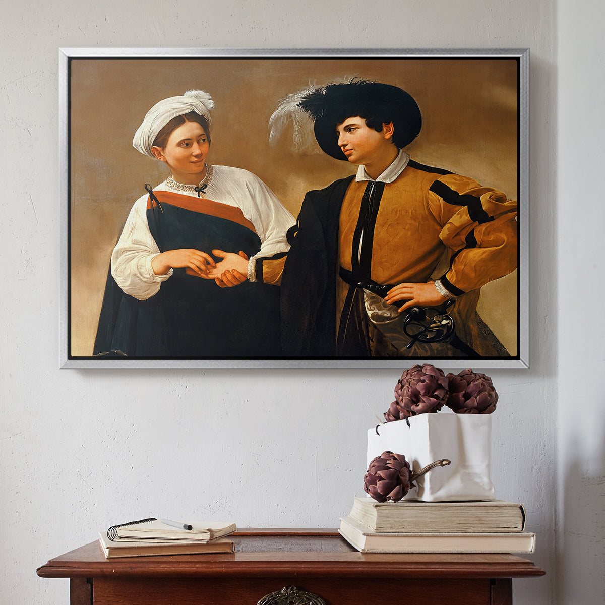 Silver floater framed canvas featuring The Fortune Teller (Capitoline Version), c. 1599 by Caravaggio above an entryway table in a minimalist foyer.