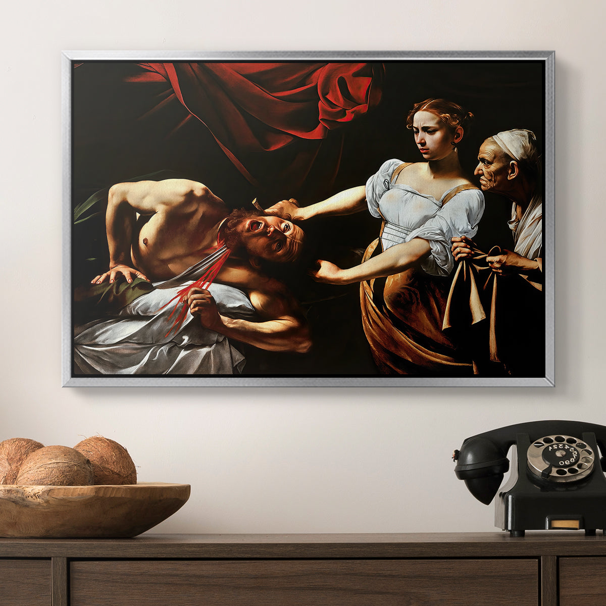 Judith Beheading Holofernes, c. 1599 by Caravaggio in a silver floater framed canvas displayed above a console table in a hallway, featuring a violent religious narrative with strong contrast of light and shadow.