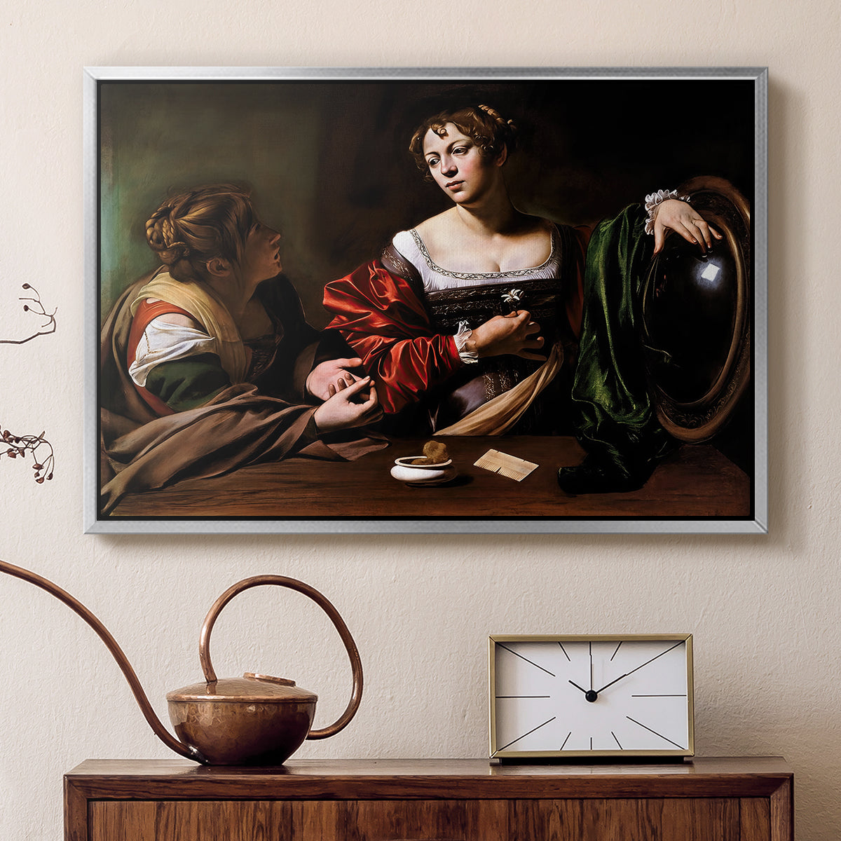 Silver floater framed canvas featuring an intimate interaction between two women with mirror and objects, displayed above a cabinet in a soft-toned living room.