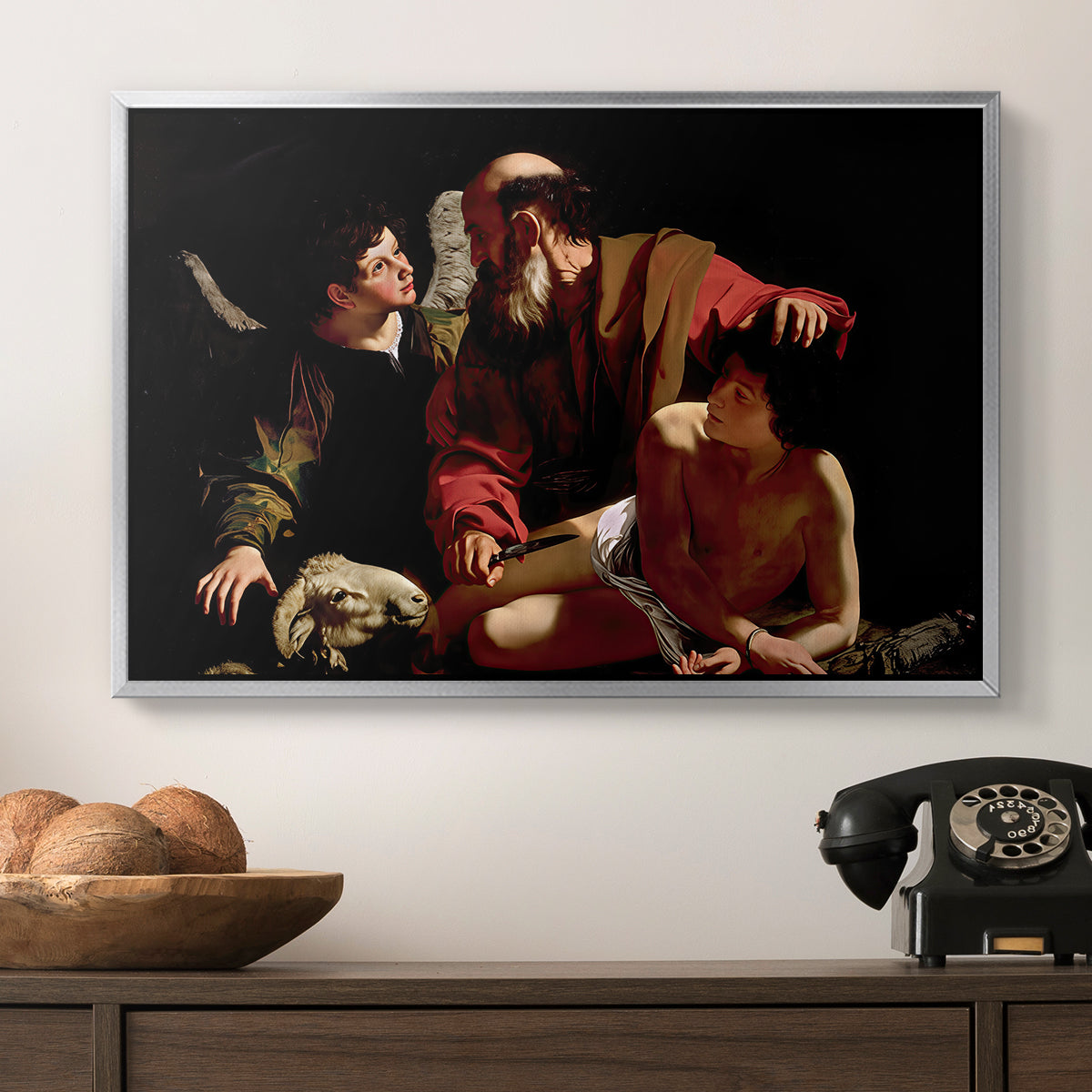 The Sacrifice of Isaac (Uffizi Version), c. 1603 by Caravaggio in a silver floater framed canvas displayed above a console table in a hallway, featuring an intense religious narrative with figures in close physical struggle.